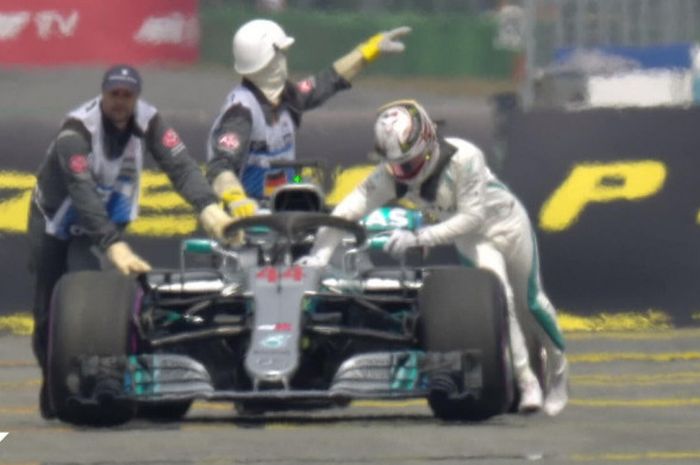 Lewis Hamilton saat mendorong mobilnya usai mengalami masalah sistem hidraulis dalam sesi kualifikasi F1 GP Jerman 2018, Sabtu (21/7/2018).