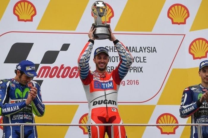 Pebalap Ducati, Andrea Dovizioso, berpose dengan trofi juara yang dia dapat setelah menjuarai GP Malaysia. Valentino Rossi (kiri) finis di urutan kedua dan Jorge Lorenzo (kanan) finis di urutan ketiga pada balapan yang berlangsung di Sirkuit Sepang, Minggu (30/10/2016).