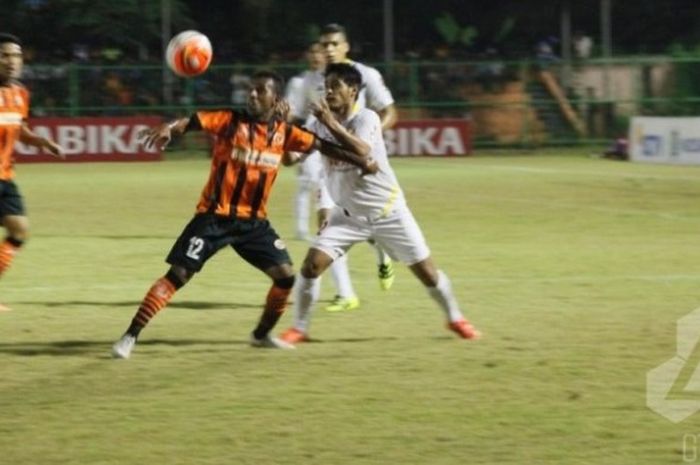 Gelandang Perseru, Boas Atururi (12) berebut bola dengan bek Semen Padang, Novan Setya di Stadion Marora, Serui, Sabtu (11/6/2016) malam. 