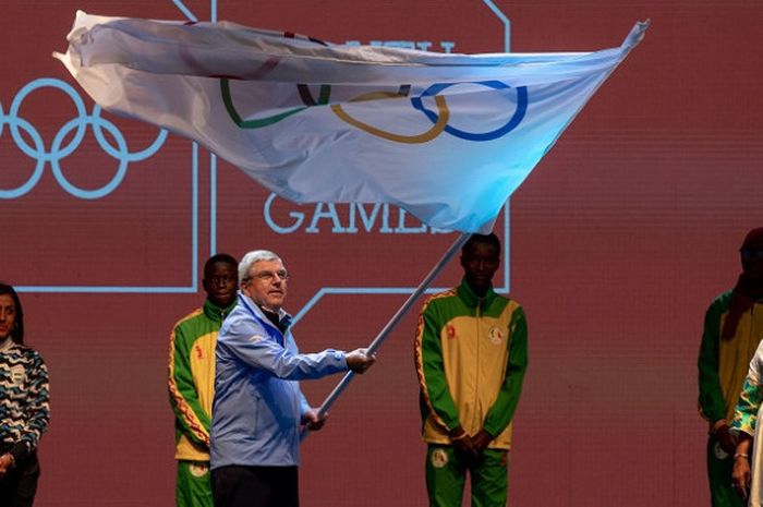 Presiden International Olympic Committee (IOC) Thomas Bach mengibarkan bendera lambang Olimpiade 