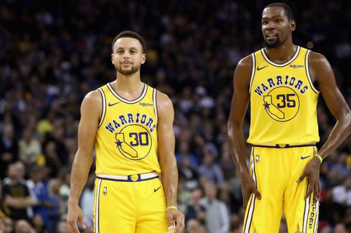 Dua pebasket bintang Golden State Warriors, Stephen Curry (kiri) dan Kevin Durant (kanan), berbincang di sela pertandingan melawan Washington Wizards di Oracle Arena, Oakland, California, AS, Rabu (24/10/2018).