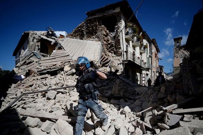 Seorang petugas berjalan di antara reruntuhan bangunan yang terdampak gempa bumi di Amatrice, Italia, 24 Agustus 2016.