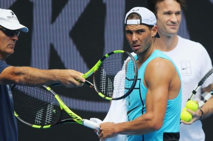 Petenis Spanyol, Raphael Nadal, mendengarkan arahan dari pelatih sekaligus pamannya, Tony Nadal (kiri), saat menjalani sesi latihan pada turnamen Australia Terbuka di Melbourne Park, Melbourne, Australia, Minggu (15/1/2017). Tampak di belakang Rafael adalah Carlos Moya yang juga menjadi pelatihnya.