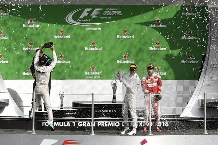 Pebalap Mercedes, Lewis Hamilton (tengah) sedang menyiramkan sampanye untuk merayakan kemenangan pada GP Meksiko yang berlangsung di Autodromo Autodromo Hermanos Rodriguez, Minggu (30/10/2016) siang  waktu setempat atau Senin (31/10/2016) dini hari WIB.