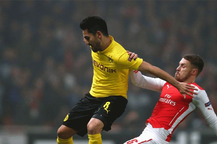 Aksi Ilkay Gundogan berebut bola dengan pemain Arsenal pada laga UEFA Championships antara Arsenal dan Borussia Dortmund di stadion Emirates, 26 November 2014. 