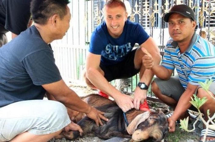 Bek Persegres asal Kroasia, Sasa Zecevic ikut memegang kambing yang akan jadi hewan kurban pada Idul Adha di Gresik, Senin (12/9/2016). 