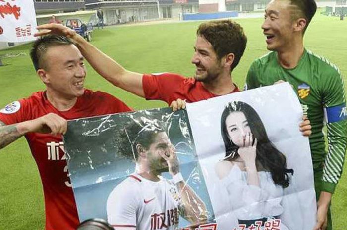Pemain Tianjin Quanjian, Alexandre Pato (tengah) bersama dua rekan setimnya memegang poster yang berisi foto dirinya bersama artis China, Dilraba Dilmurat, yang diberikan fans, setelah menang 4-1 atas Jeonbuk Motors di Liga Champions Asia, Rabu (14/3/2018)