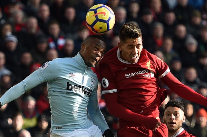 Bek West Ham United, Patrice Evra, kala melakoni duel udara dengan striker Liverpool, Roberto Firmino, pada pertandingan di Stadion Anfield, Sabtu (24/2/2018).