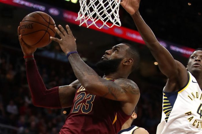 Pemain bintang, LeBron James (jersey merah, #23), berupaya melepaskan tembakan lay-up seraya dijaga  pebasket Indiana Pacers, Victor Oladipo, pada laga musim reguler NBA di Quicken Loans Arena, Cleveland, Ohio, Amerika Serikat, Rabu (1/11/2017) malam waktu setempat.