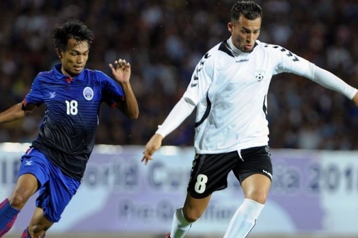 Pemain Afghanistan, Faysal Shayesteh (kanan), menggiring bola demi menjauh dari pemain Kamboja