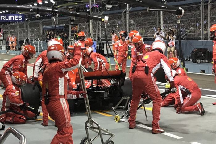 Pebalap Ferrari Sebastian Vettel melakukan pitstop pada lap ke-15 balapan GP Singapura di Sirkuit Jalan Raya Marina Bay, Singapura, Minggu (16/9/2018).