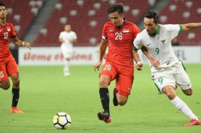 Striker Timnas U-23 Indonesia Ezra Walian berebut bola dengan bek Timnas U-23 Singapura Illyas Lee dalam uji coba internasional di Stadion Nasional, Singapura, Rabu (21/3/2018) malam WIB.