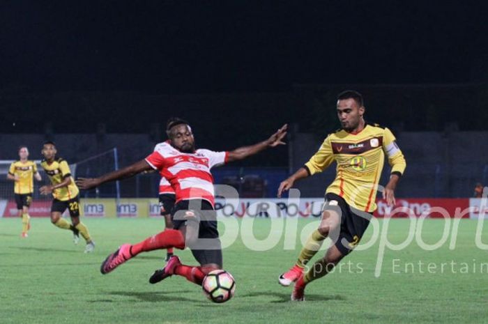 Aksi pemain Madura United, Engelberd Sani, versus kapten Barito Putera, Rizky Pora, pada lanjutan laga Liga 1, Minggu (5/11/2017).