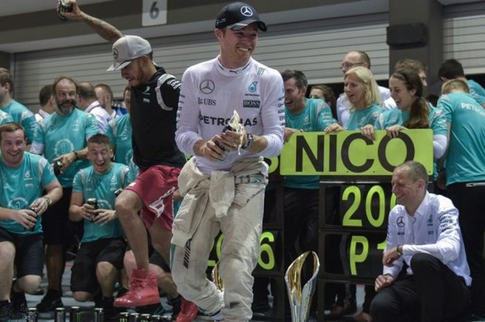 Pebalap Formula 1 (F1) asal Jerman yang membela tim Mercedes AMG Petronas, Nico Rosberg (tengah), merayakan kemenangan pada GP Singapura bersama runner-up sekaligus rekan setimnya, Lewis Hamilton (kiri belakang), dan anggota tim lain di Sirkuit Marina Bay Street, Singapura, Minggu (20/9/2016).