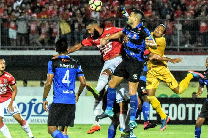 Striker Bali United, Sylvano Comvalius melompat berduel udara dengan kapten Madura United, Fabiano Rosa Beltrame pada laga pekan ke-19 Liga 1 di Stadion Kapten I Wayan Dipta, Gianyar, Minggu (13/8/2017).