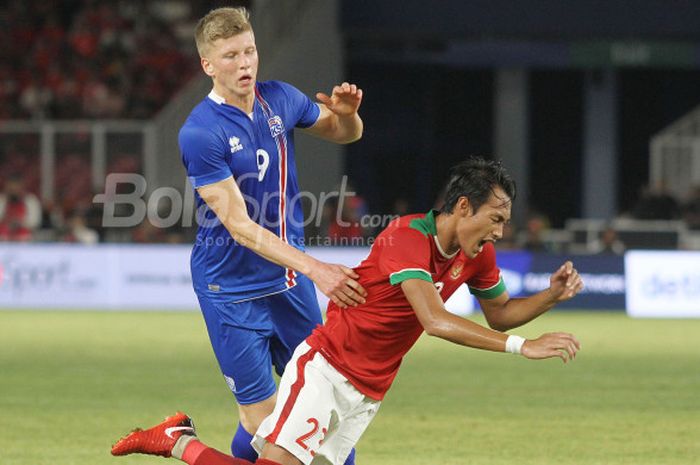 Bek timnas Indonesia, Hansamu Yama Pranata terjatuh setelah berduel dengan pemain Islandia, Ottar Magnus Karlsson, pada laga  uji coba internasional di Stadion Utama GBK, Jakarta Selatan, Minggu (14/1/2018) malam. 