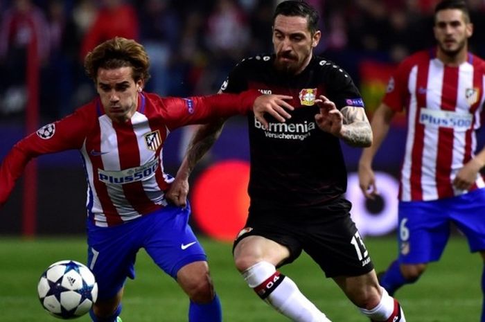 Penyerang Atletico Madrid, Antoine Griezmann berusaha melewati hadangan pemain Bayer Leverkusen, Roberto Hilbert di laga penentuan babak 16 besar Liga Champions, Rabu (15/3/2016) waktu setempat.