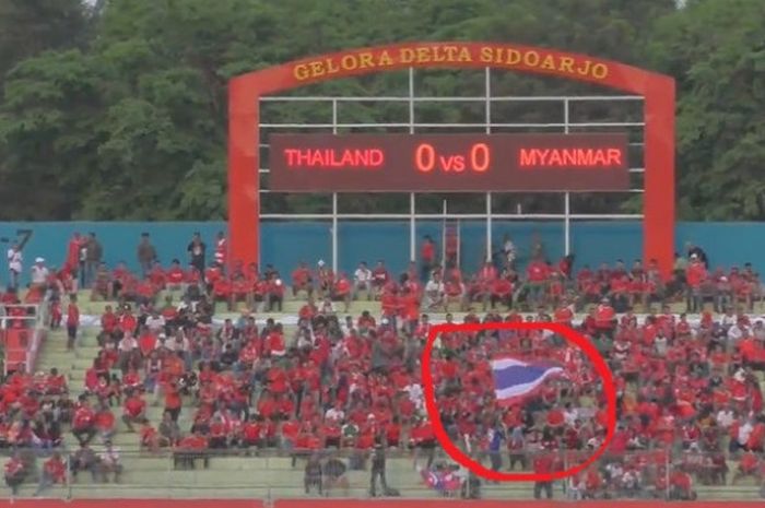Salah seorang pendukung timnas U-16 Thailand mengibarkan bendera di tengah kerumunan suporter Indonesia di Stadion Gelora Delta, Sidoarjo pada Kamis (9/8/2018).
