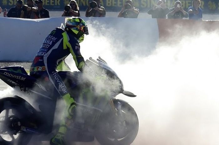 Pebalap Movistar Yamaha, Valentino Rossi,menampilkan aksi mengepulkan asap setelah menjalani balapan GP Valencia di Sirkuit Ricad=rdo Tormo, Minggu (13/11/2016).