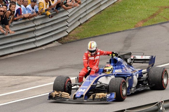 Pebalap Ferrari asal Jerman, Sebastian Vettel, menumpang mobil Pascal Wehrlein (Sauber) setelah mengalami insiden dengan Lance Stroll (Williams) pada akhir balapan GP Malaysia di Sirkuit Sepang, Minggu (1/10/2017).