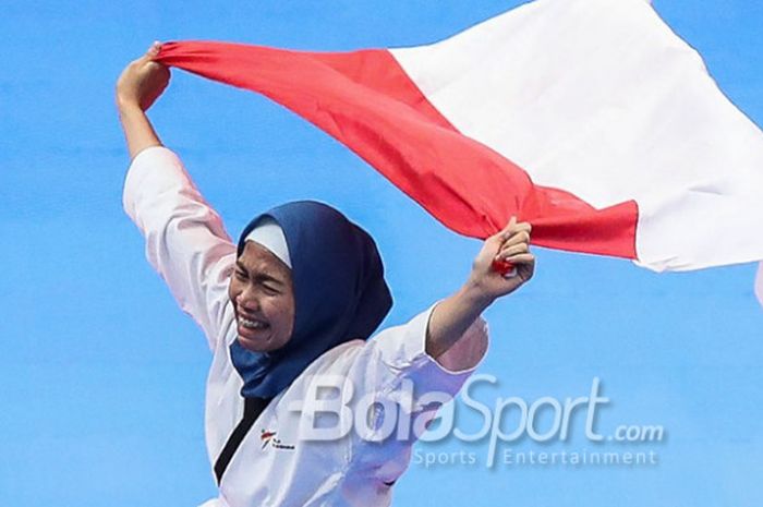 Atlet taekwondo, Defia Rosmaniar, merayakan keberhasilannya meraih medali emas pada nomor poomsae individu putri di Plenary Hall JCC, Jakarta, Minggu (19/8/2018).