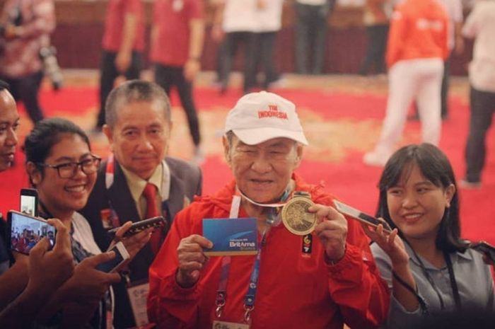 Bambang Hartono membawa medali emas dan buku tabungan BRI saat diundang ke Istana Presiden, Minggu (2/9/2018)