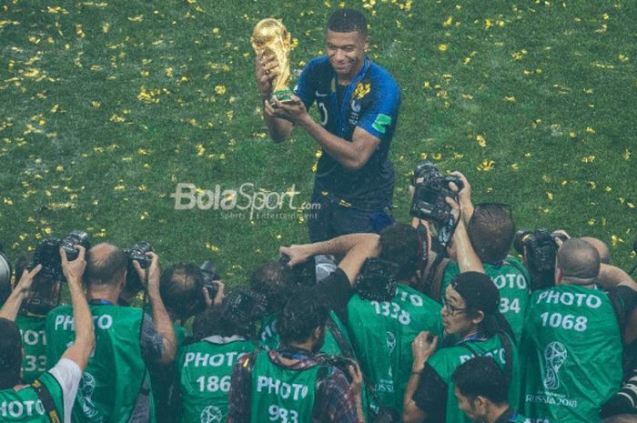   Penyerang Prancis, Kylian Mbappe, berpose dengan trofi juara Piala Dunia 2018 setelah timnya menekuk Kroasia 4-2 pada laga final di Stadion Luzhniki, Moskow, 15 Juli 2018.  