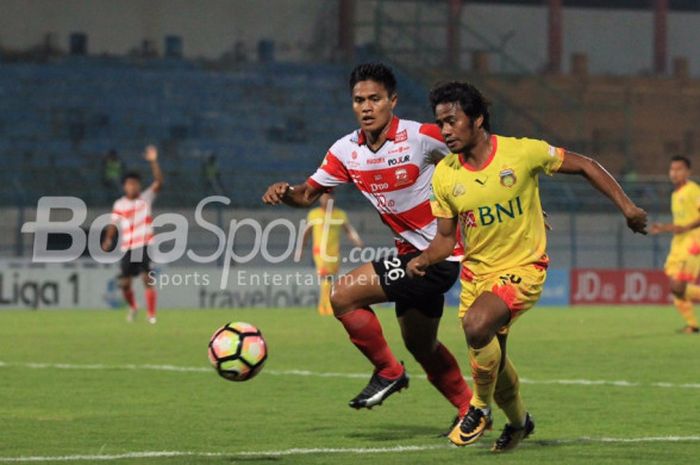 Pemain sayap Bhayangkara FC Ilham Udin Armayn dibayang-bayangi bek Madura United Fachrudin Aryanto pada pertandingan Liga 1, Rabu (8/11/2017) malam WIB, di Stadion Gelora Bangkalan, Jawa Timur. 