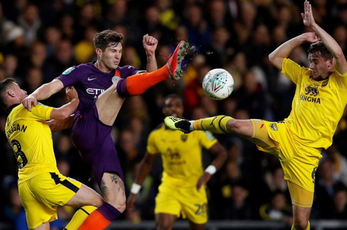 Aksi bek Manchester City, John Stones (tengah), saat berduel dengan gelandang Oxford United, Cameron Brannagan (kiri) dan Jamie Hanson (kanan), dalam laga ronde ke-3 Piala Liga Inggris 2018-2019 di Stadion Kassam, Oxford, Inggris, pada Selasa (25/9/2018).