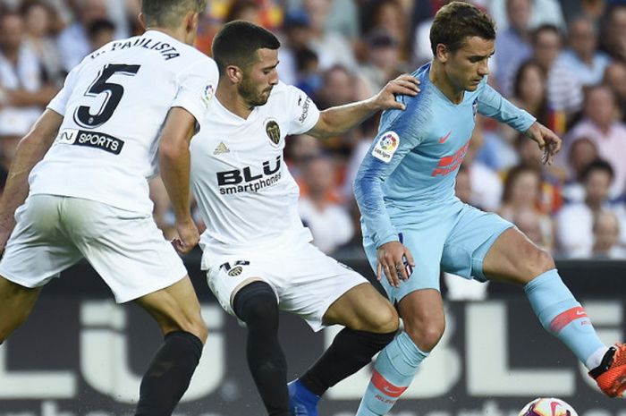 Antoine Griezmann mencoba melewati bek Valencia, Jose Luis Gaya Pena dan Gabriel Paulista saat berlaga di laga Valencia Vs Atletico Madrid di Stadion Mestalla, Valencia pada Senin (20/8/2018)