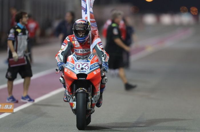 Pebalap Ducati, Andrea Dovizioso, mengitari lintasan sambil mengibarkan bendera setelah memenangi GP Qatar di Sirkuit Internasional, Losail, Minggu (18/3/2018).