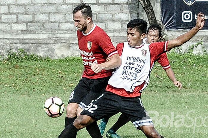 Ahmad Agung (rompi putih) berupaya menjegal rekan setimnya Ilija Spasojevic (merah) saat sesi game internal Bali United di Lapangan Trisakti, Legian, Senin (8/1/2018).