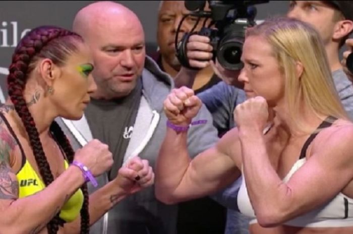 Cris Cyborg (kiri) dan Holly Holm (kanan) yang ditengahi oleh Presiden UFC, Dana White, saat saling berhadapan seusai sesi timbang badan jelang UFC 219.