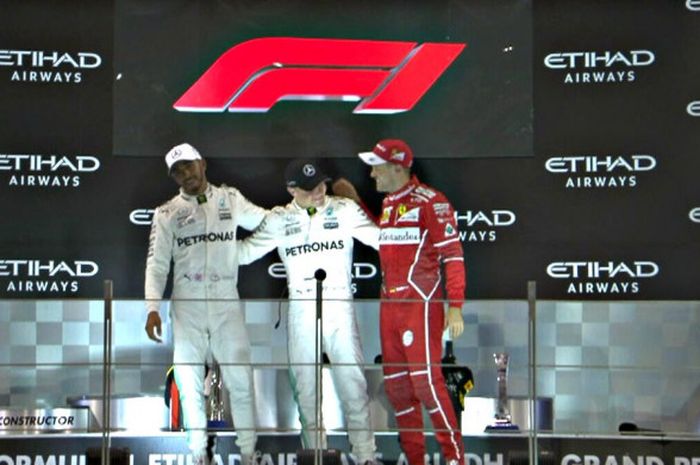 Peraih podium, Lewis Hamiton (kiri) dan Sebastian Vettel (kanan) menyelemati pemenang balapan GP Abu Dhabi Valtteri Bottas (tengah) yang berlangsung di Sirkuit Yas Marina, Minggu (26/11/2017).