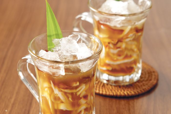 Rujak degan yang disajikan dalam batok kelapa, memberikan kesan alami dan segar dengan tambahan irisan cabai merah dan daun mint