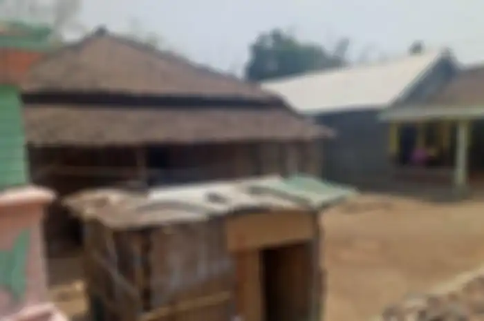 Tampak sebuah tempat tidur (dipan), kursi dan meja kecil di dalam rumah yang masih beralas tanah.   