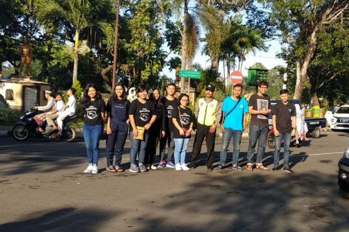 Belasan pemuda dan pemudi itu tampak mengenakan kaus hitam dengan tulisan "Aku Kancamu" dan gambar dua tangan saling menjabat.
