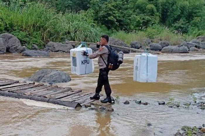 Sebuah foto menunjukkan bagaimana polisi mengawal kotak suara yang berisi surat suara hasil pencoblosan melewati sungai dengan jembatan seadanya.