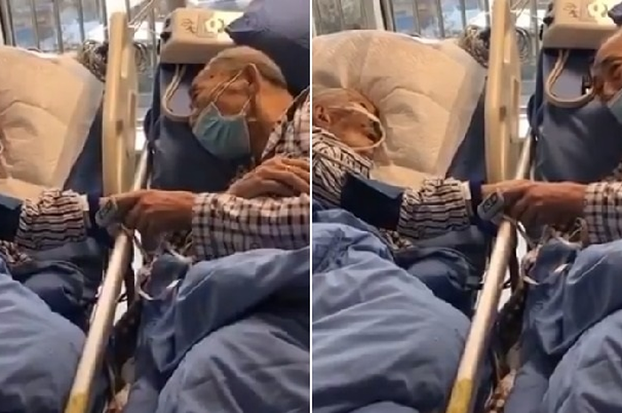 Sang istri terhubung ke beberapa peralatan medis sementara sang suami terbaring lemah tetapi masih menggenggam tangan istrinya.