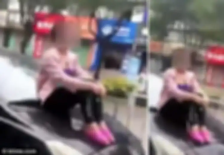 Tak Ingin Suaminya Pergi, Wanita Ini Duduk di Kap Mobil yang Sedang Berjalan. Videonya Bikin Geli