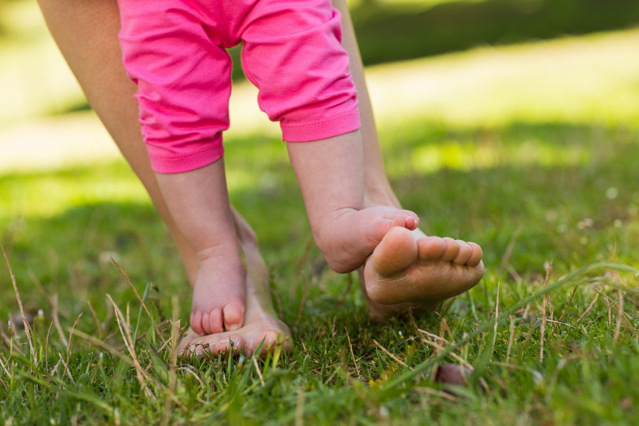 Baby girl barefoot grass. Child legs