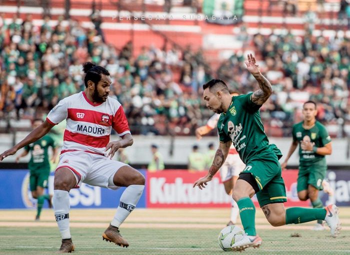 Bek Madura United, Fandry Imbiri (kiri) berebut bola dengan pemain Persebaya, Damian Lizio (kanan), pada laga leg pertama babak 8 besar Piala Indonesia 2018 di Stadion Gelora Bung Tomo, Rabu (19/6/2019).