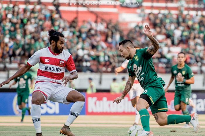 Pemain Persebaya, Damian Lizio (kanan), berebut bola dengan bek Madura United, Fandry Imbiri (kiri) pada laga leg pertama babak 8 besar Piala Indonesia 2018 di Stadion Gelora Bung Tomo, Rabu (19/6/2019).