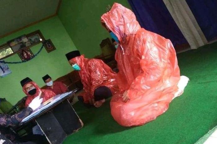 Terbungkus Jas Hujan dan Tertutup Masker Sepasang  