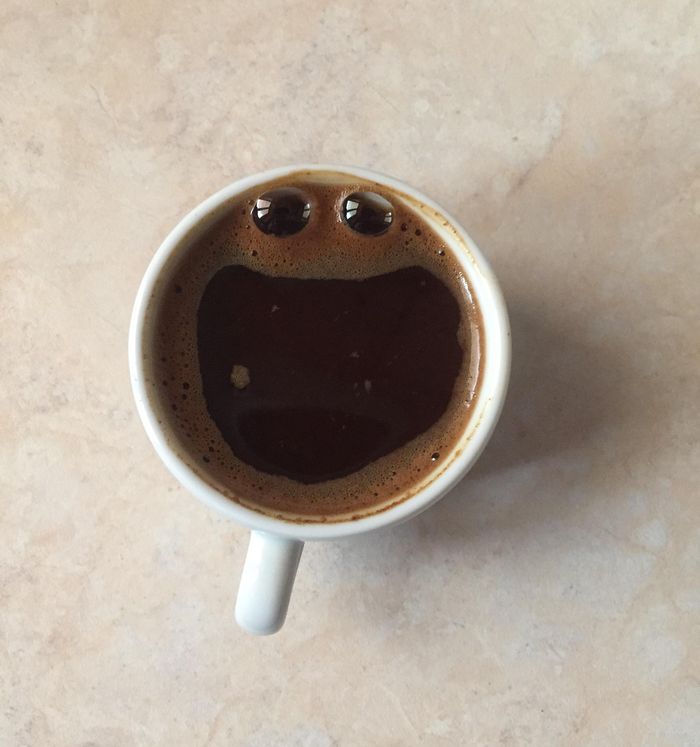 A cup of coffee that evokes pareidolia, our image of the human face.  