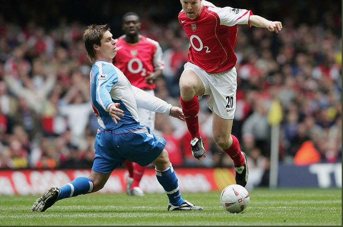 Bek Arsenal, Philippe Senderos, saat mencoba melewati pemain tim lawan dalam sebuah pertandingan.