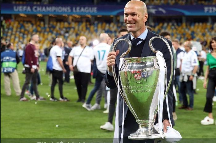 Pelatih Real Madrid, Zinedine Zidane, memegangi trofi juara Liga Champions.