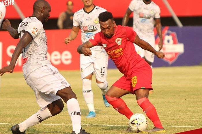 Striker Kalteng Putra, Patrich Wanggai, berusaha melewati pemain bertahan Tira-Persikabo, Zoubairou, pada laga pekan ke-29 Liga 1 2019.