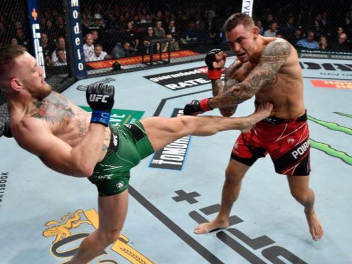 Conor McGregor (kiri) saat melakukan tendangan untuk menyeranga Dustin Poirier pada duel trilogi pada UFC 264 di T-Mobile Arena, Las Vegas, Nevada, AS, Minggu (11/7/2021).