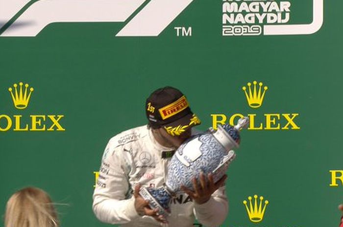 Pembalap Mercedes, Lewis Hamilton (tengah) mencium trofi setelah menjadi juara Formula 1 GP Hungaria di Hungaroring, Minggu (4/8/2019).